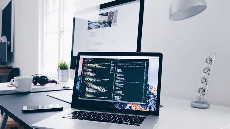 Desk with computers with code on the screen